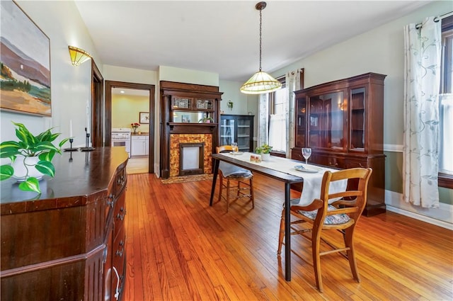dining room featuring a fireplace with flush hearth and wood-type flooring