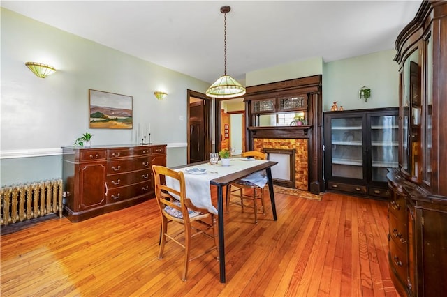 dining area with radiator, a fireplace, and light wood-style flooring