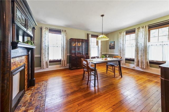 dining space featuring hardwood / wood-style floors, a fireplace, and baseboards