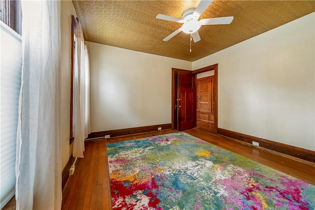 unfurnished room with baseboards, ceiling fan, and wood finished floors