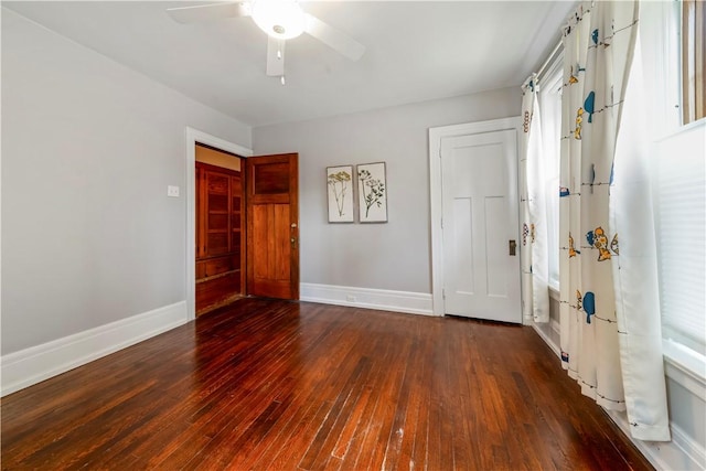 empty room with dark wood-type flooring, baseboards, and a ceiling fan