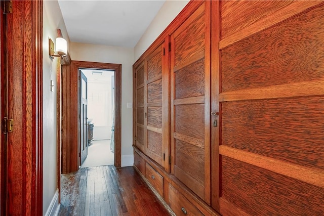 hallway featuring dark wood-style floors and baseboards