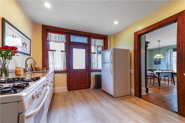 kitchen with white appliances, a sink, light wood-style flooring, plenty of natural light, and recessed lighting