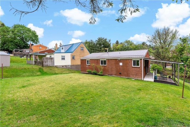 rear view of house featuring brick siding, a patio, metal roof, and crawl space