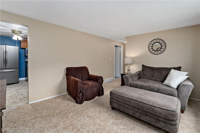 living area featuring a ceiling fan, light colored carpet, and baseboards