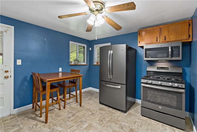 kitchen with appliances with stainless steel finishes, baseboards, brown cabinets, and ceiling fan