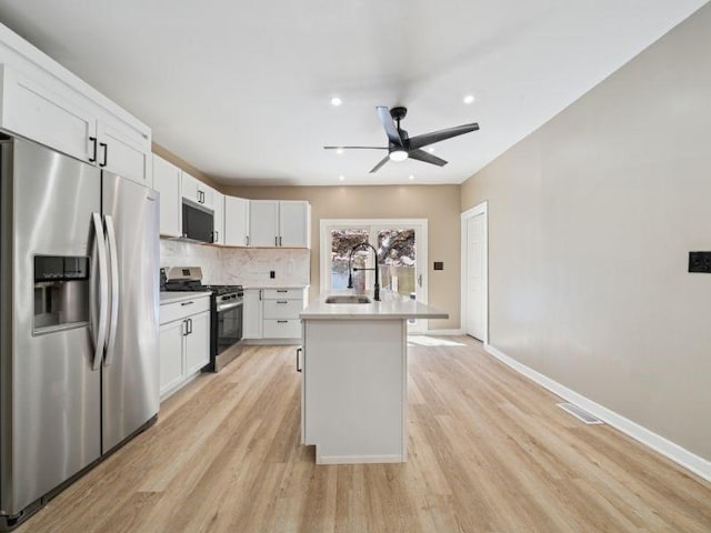 232 57th St, Lawrenceville, PA 15201 - kitchen featuring stainless steel appliances, a sink, light wood-style floors, light countertops, and an island with sink