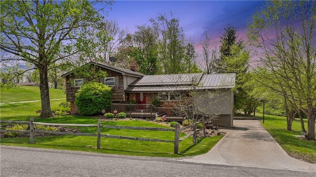 split level home with driveway, covered porch, metal roof, a standing seam roof, and a chimney