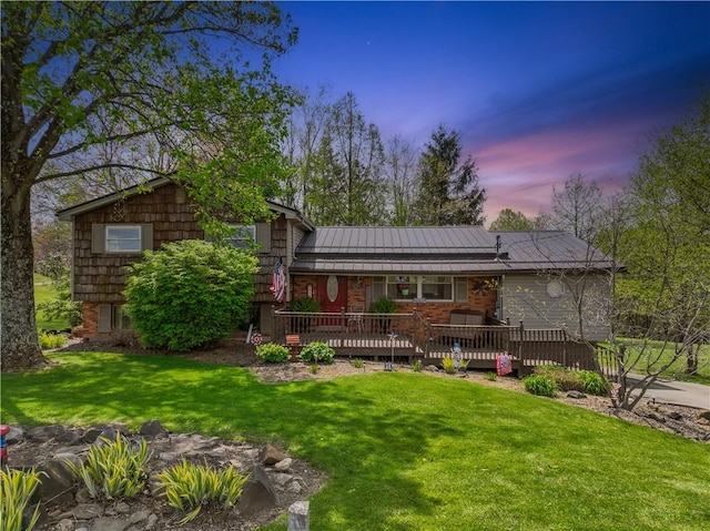 back of house featuring a lawn, a standing seam roof, metal roof, and a wooden deck