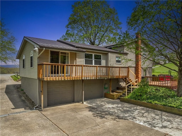 view of front of home with a garage, metal roof, driveway, and stairs