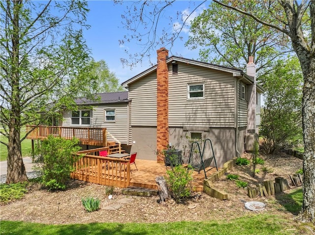 rear view of house with a wooden deck, a chimney, and metal roof