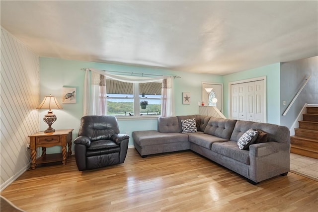 living room featuring light wood-style floors, stairs, and baseboards