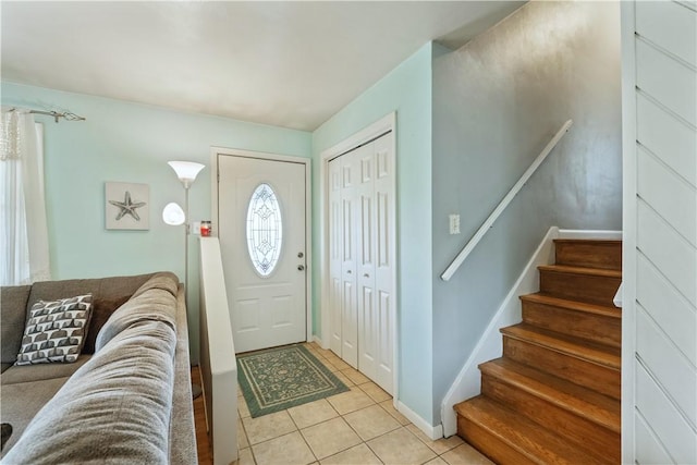foyer with light tile patterned flooring, stairway, and baseboards