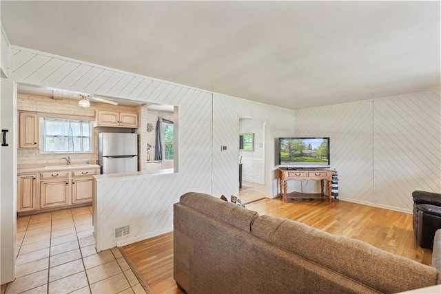 living area featuring light wood-style flooring, baseboards, and wood walls