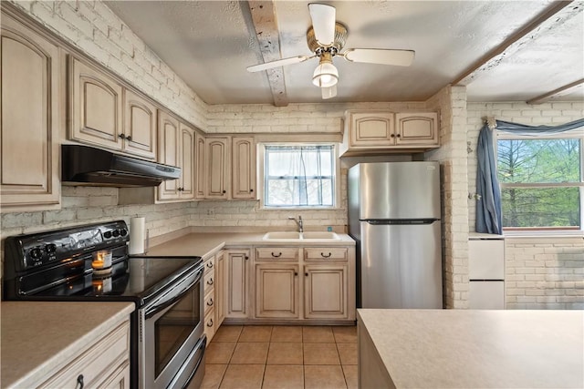 kitchen featuring appliances with stainless steel finishes, under cabinet range hood, a sink, light countertops, and healthy amount of natural light