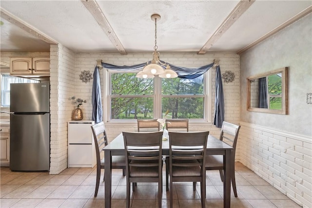 dining area featuring light tile patterned floors, beam ceiling, brick wall, and a chandelier