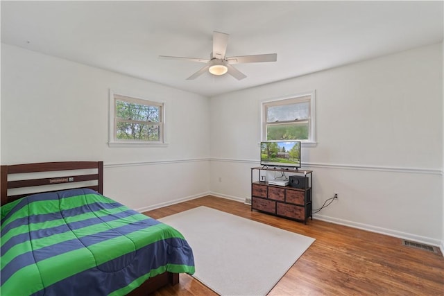 bedroom featuring wood finished floors, baseboards, and a ceiling fan
