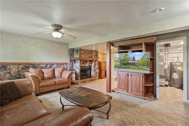 living area with water heater, a stone fireplace, a ceiling fan, light carpet, and a textured ceiling