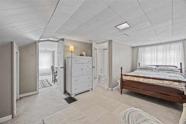carpeted bedroom with baseboards, connected bathroom, and vaulted ceiling