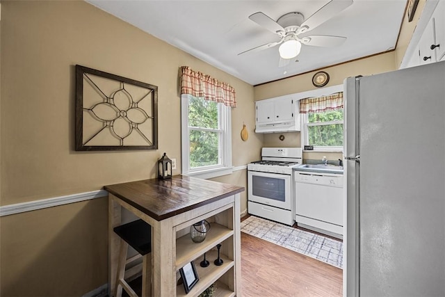 kitchen with white appliances, under cabinet range hood, a ceiling fan, white cabinets, and a sink