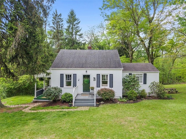cape cod house featuring a front lawn, a chimney, and a shingled roof