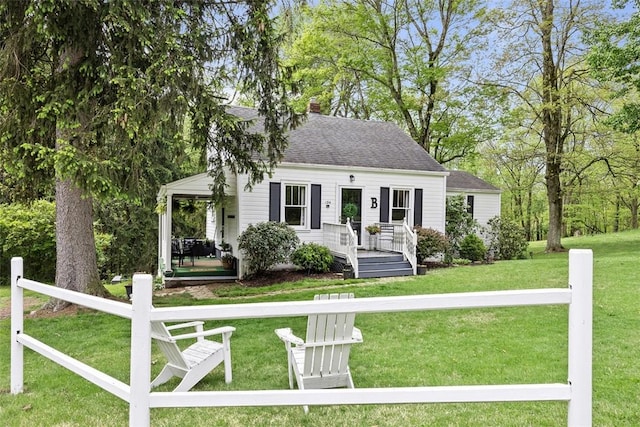 view of front of property with a front yard, a chimney, a porch, and roof with shingles