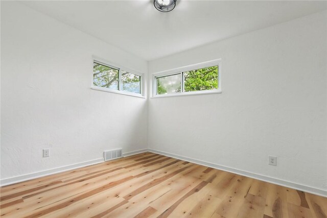 spare room featuring plenty of natural light, baseboards, and wood finished floors