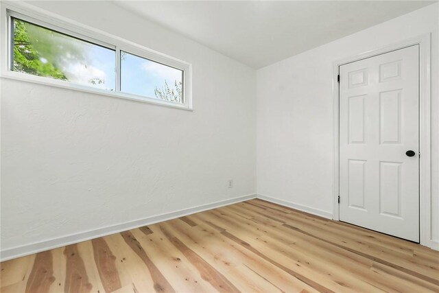 empty room featuring healthy amount of natural light, baseboards, and light wood-style flooring