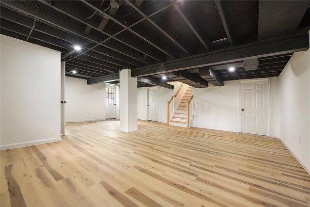 below grade area featuring stairs, wood finished floors, and baseboards