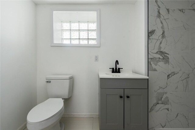 bathroom with vanity, toilet, baseboards, and a shower