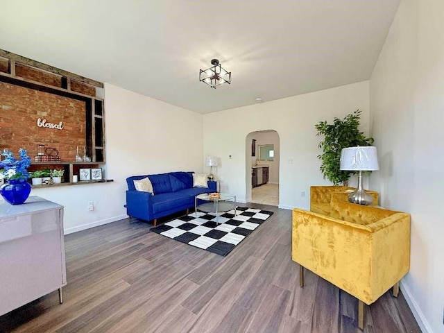 living room featuring arched walkways, wood finished floors, and baseboards