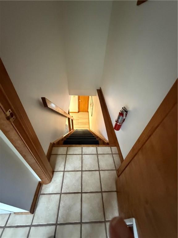 stairway with tile patterned floors and baseboards