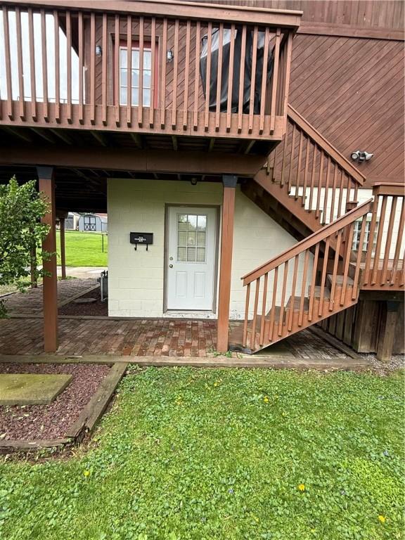 view of exterior entry featuring concrete block siding and a lawn