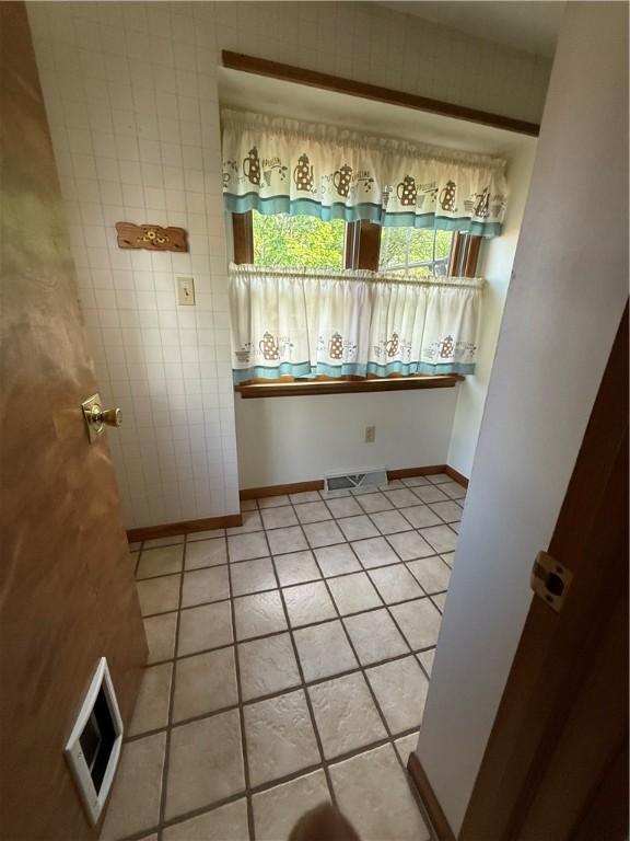 unfurnished dining area with light tile patterned floors and baseboards