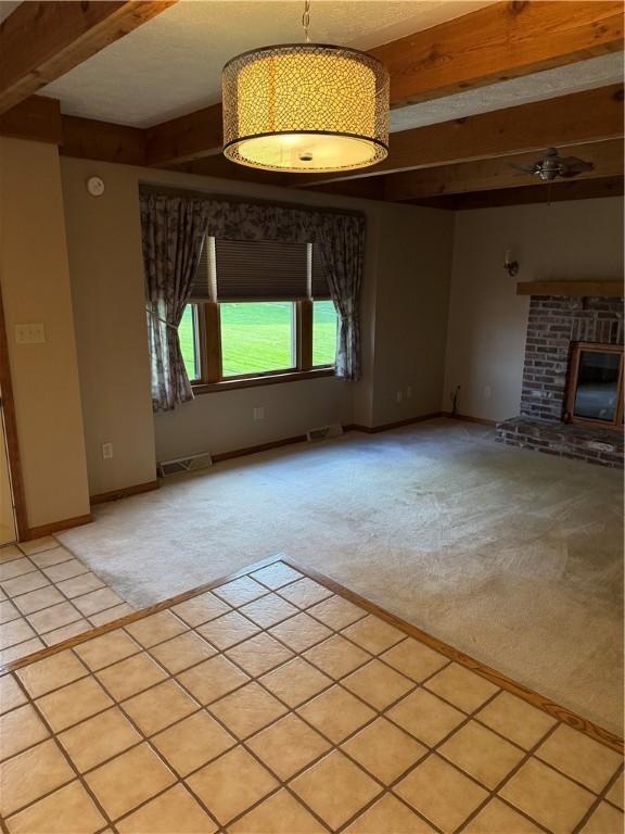 unfurnished living room with beam ceiling, light carpet, a fireplace, and baseboards
