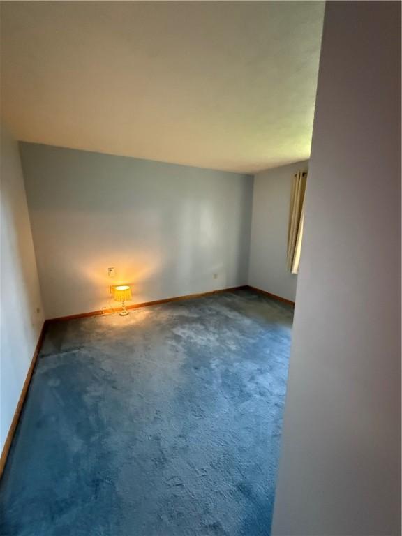 carpeted spare room featuring baseboards