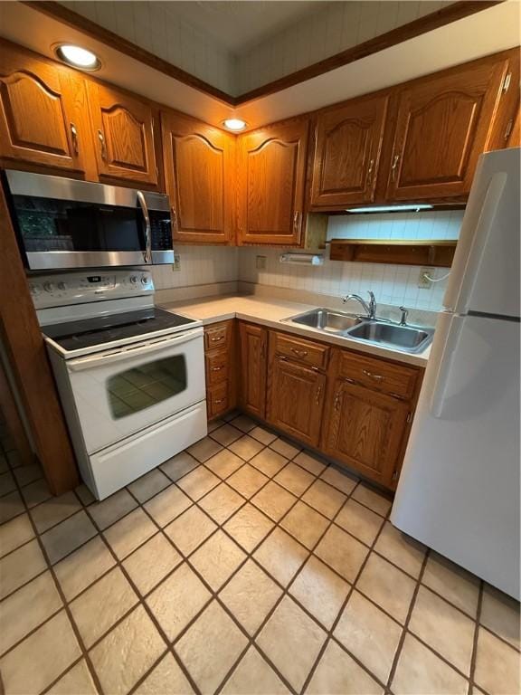 kitchen featuring white appliances, a sink, brown cabinets, and light countertops