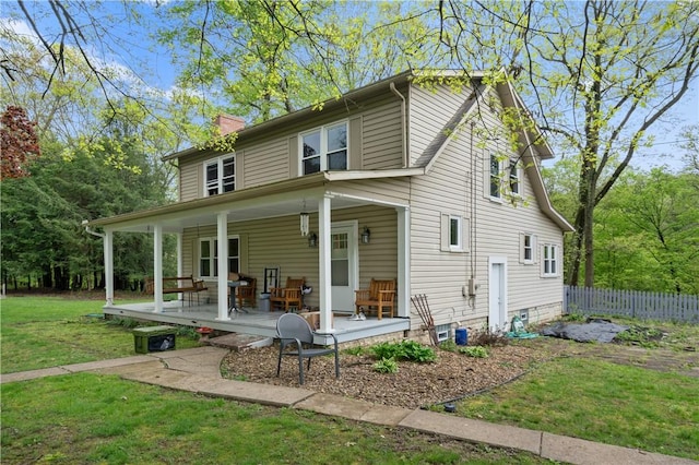 rear view of property featuring a chimney and a porch