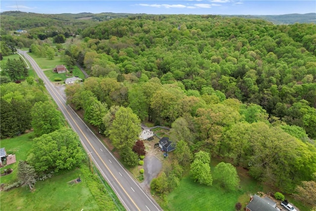 aerial view of property and surrounding area featuring a heavily wooded area