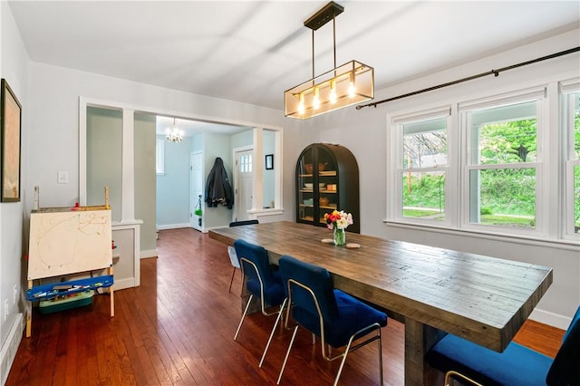 dining room with a chandelier, dark wood-type flooring, and baseboards