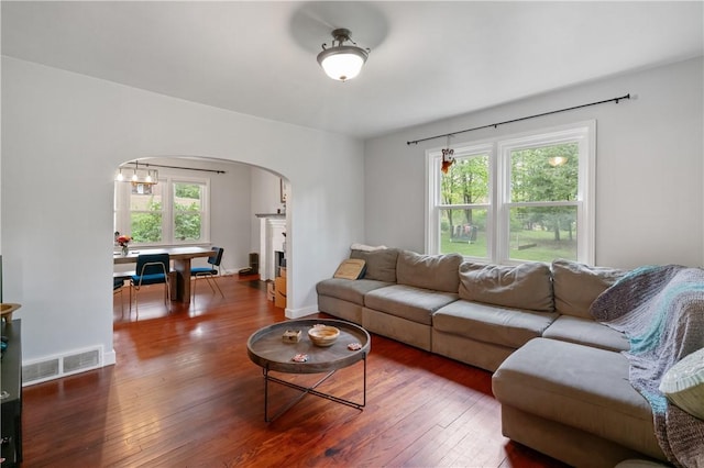 living area featuring arched walkways, plenty of natural light, hardwood / wood-style floors, and baseboards