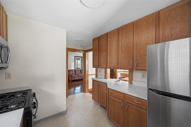 7208 Raymond St, Swissvale, PA 15218 - kitchen with stainless steel appliances, light countertops, brown cabinetry, and light flooring