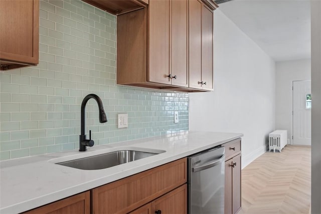 kitchen with a sink, stainless steel dishwasher, light countertops, and backsplash