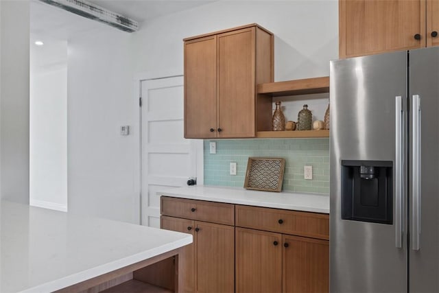 kitchen featuring stainless steel fridge, open shelves, decorative backsplash, light countertops, and brown cabinets