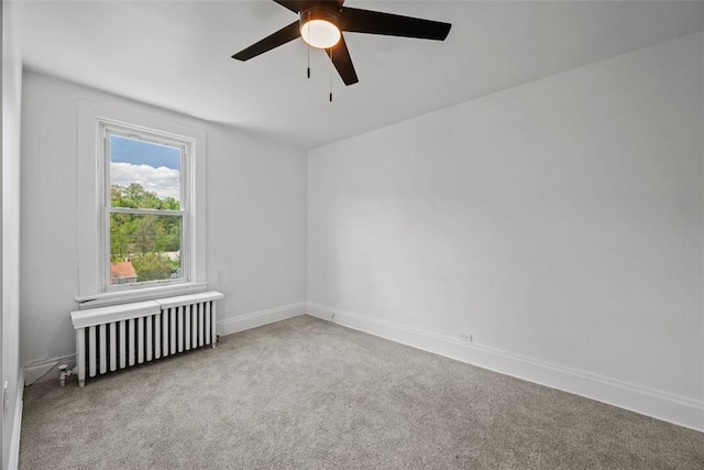 carpeted empty room with radiator heating unit, a ceiling fan, and baseboards