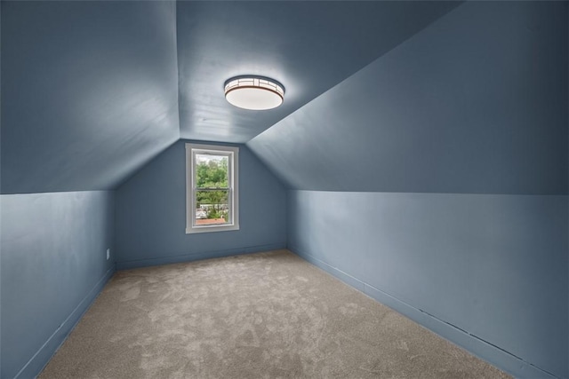 additional living space featuring carpet flooring, lofted ceiling, and baseboards