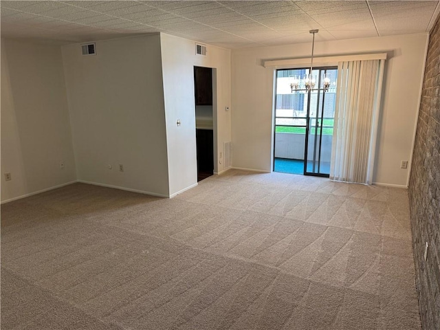 spare room featuring a chandelier, light colored carpet, and baseboards