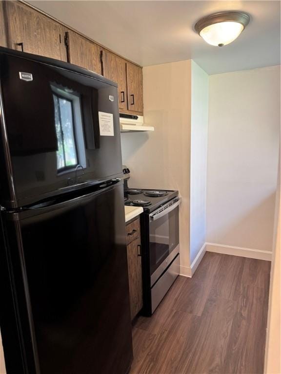 kitchen featuring freestanding refrigerator, stainless steel range with electric stovetop, under cabinet range hood, dark wood-style flooring, and brown cabinets