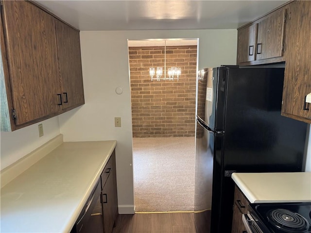 kitchen featuring stainless steel range with electric cooktop, light countertops, a chandelier, dark wood-type flooring, and freestanding refrigerator