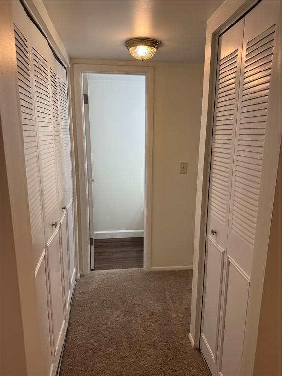 hallway featuring carpet and baseboards